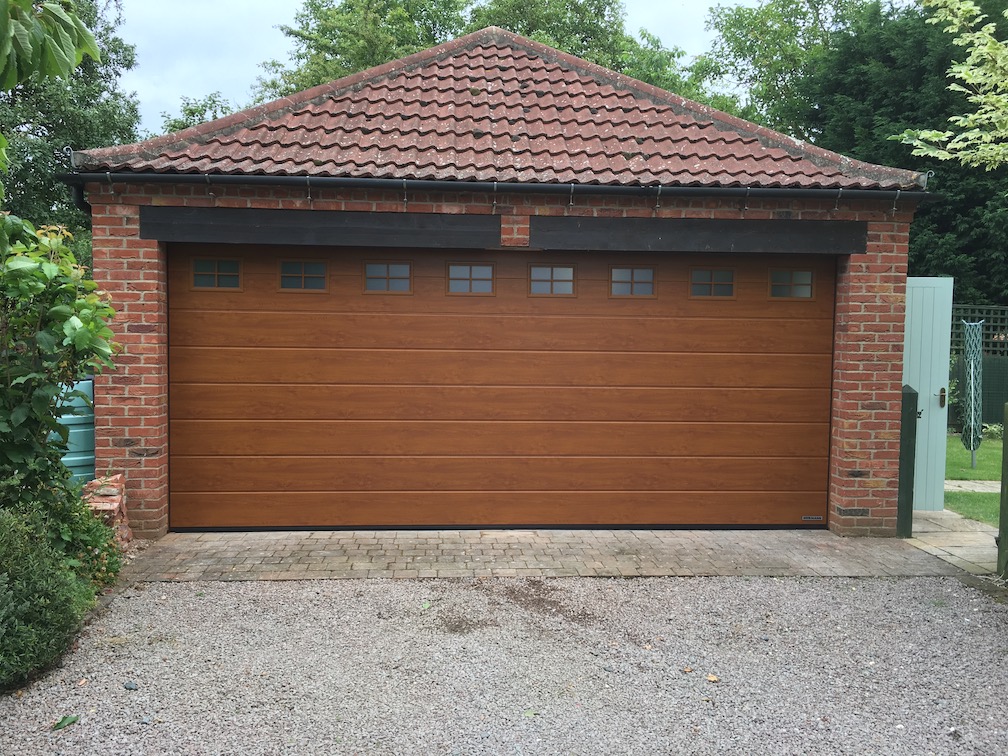 A Hörmann Sectional door M-Ribbed Golden Oak with windows